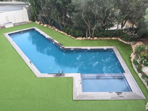 - une vue sur la piscine sur une pelouse verdoyante dans l'établissement STUDIO de STANDING avec VUE MER, PISCINE, WIFI, à Porto-Vecchio