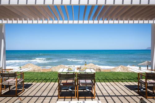 een patio met een tafel en stoelen en het strand bij The Mini Beach Hotel in Stalós
