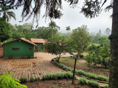 ein grünes Haus mitten auf einem Feld in der Unterkunft Pousada La na Roça in Paraisópolis