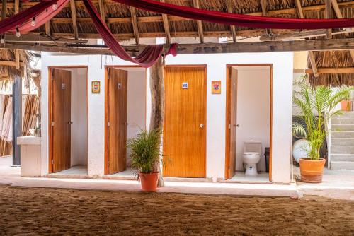 a bathroom with four doors and a toilet at Che Zipolite Hostel & Naked Beach Club in Zipolite