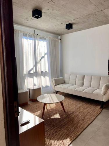 a living room with a white couch and a table at Moderno apartamento en Carmelo in Carmelo