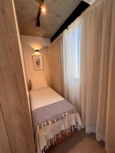 a small bed in a room with a window at Moderno apartamento en Carmelo in Carmelo