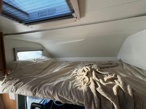 Cama en habitación pequeña con ventana en Camping Van en Keflavík