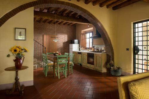 cocina con arco y mesa con sillas en Il Coltro, en San Gimignano