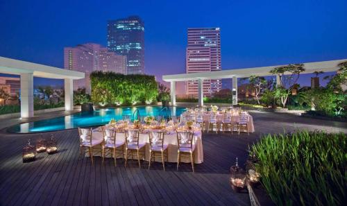 ジャカルタにあるMandarin Oriental, Jakartaのテーブルと椅子付きの宴会場、プールを提供しています。