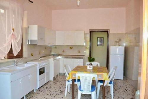 una cucina con tavolo, sedie e armadietti bianchi di Giordano Villa Oleandro a Borgo Bonsignore