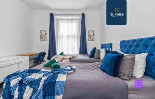 a bedroom with two beds and a blue headboard at THE DENS, 3 Rooms, 4 Beds, 2 Bathrooms, Fully Equipped, Wifi, Parking, Mid-Long Stays Rates Available by SUNRISE SHORT LETS in Dundee
