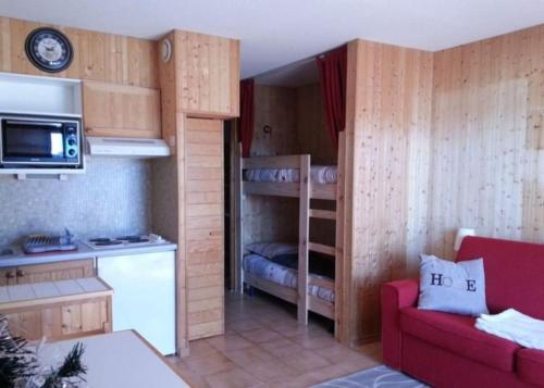 une petite chambre avec des lits superposés et un canapé rouge dans l'établissement T2 très bien placé aux Angles, aux Angles