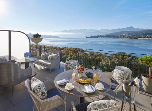 a patio with tables and chairs and a view of the water at Mandarin Oriental Palace, Luzern in Luzern