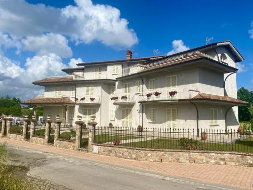 une grande maison blanche avec une clôture dans une rue dans l'établissement -Casa Vacanza Il Glicine- Immerso Nel Verde, à Altopascio