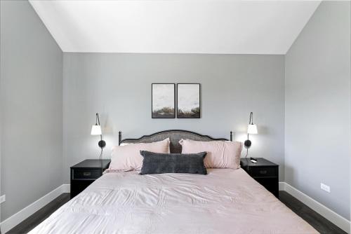 a white bedroom with a large bed with pink pillows at Just a Little Longer in Ottawa