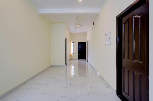 um corredor vazio com uma porta e um piso branco em OYO Flagship SIVANANDA HOMESTAY em Varkala