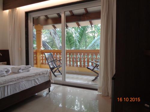 a bedroom with a balcony with a bed and a sliding glass door at Palolem Guest House in Palolem