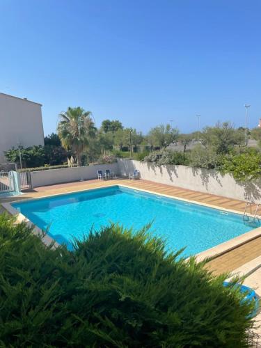 une grande piscine bleue à côté d'un immeuble dans l'établissement Appart Cap d’Agde, au Cap d'Agde
