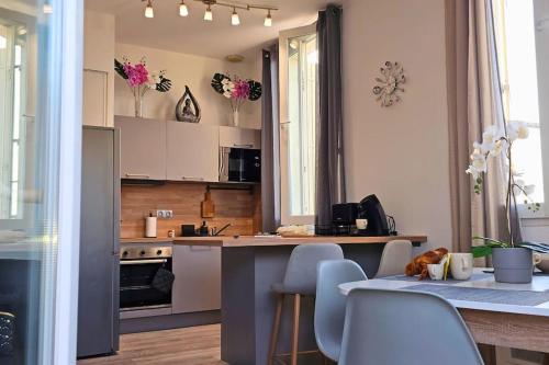 ナルボンヌにあるL'Orchidée, proche de la gare avec clim et terrasseの白いキャビネットとテーブルと椅子のあるキッチン