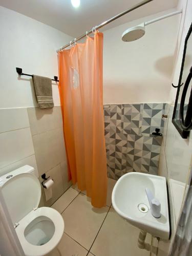 a bathroom with an orange shower curtain and a toilet at Apartamento no centro para Casal in Mata de Sao Joao