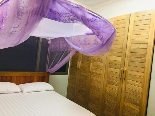 a bedroom with a bed with purple mosquito netting at Grand Grove Villa in Jinja