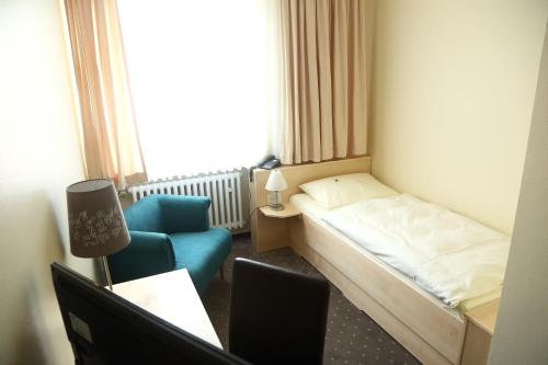 a hotel room with a bed and a chair at Bürgermeisterkapelle in Hildesheim