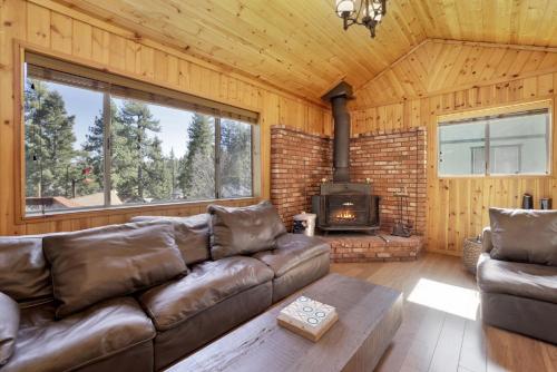 een woonkamer met een leren bank en een open haard bij 2259-Fawnskin Pines cabin in Fawnskin