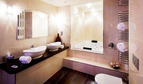 a bathroom with two sinks and a mirror and a tub at Applegarth Villa Hotel & Restaurant (Adult Only) in Windermere
