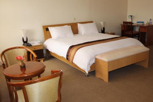 a bedroom with a large bed and a table and chairs at Virunga Hotel in Ruhengeri