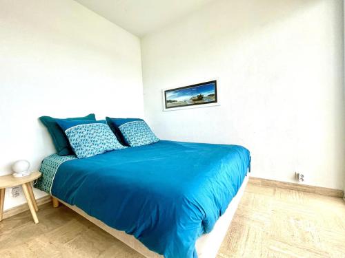 une chambre avec un lit bleu dans une pièce blanche dans l'établissement Studio sur les quais d'Etel, à Étel