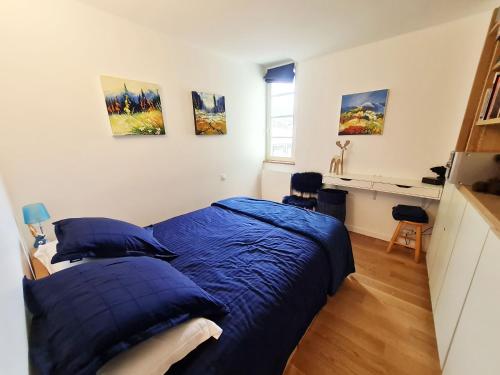 Cette chambre comprend un lit avec des draps bleus et un bureau. dans l'établissement Appartement les 3 Flocons Cauterets, à Cauterets