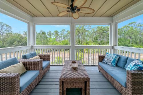 a screened porch with couches and a ceiling fan at Carlinga Cottage at Lost Key Golf & Beach Club in Pensacola