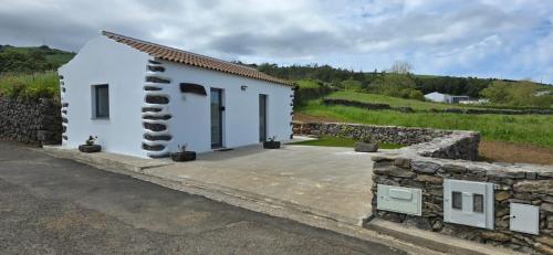 a small white house with a stone wall at Casa do Avô José Mota in Santa Cruz das Flores