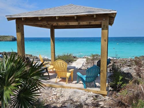 a wooden gazebo with chairs and the ocean at Paradise Cove home in Gregory Town
