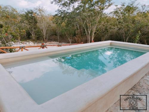 a pool with blue water and trees in the background at Aldea Ek Balam Valladolid in Valladolid
