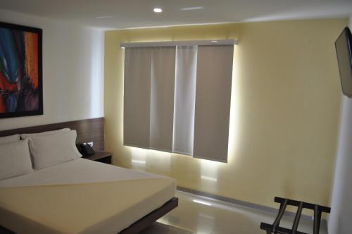a bedroom with a white bed and a window at Hotel Mio Boutique in Cúcuta