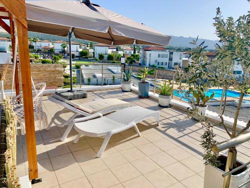 a patio with an umbrella and a table and chairs at Boho Bay Apartment in Akanthou