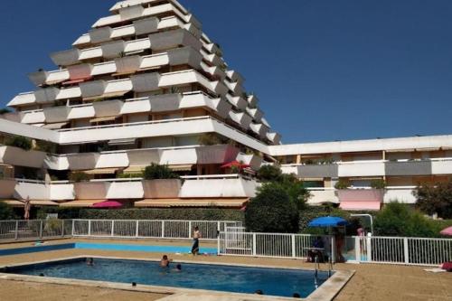un immeuble avec une piscine devant un immeuble dans l'établissement T2 moderne ,design, neuf, climatisé avec piscine, à La Grande Motte