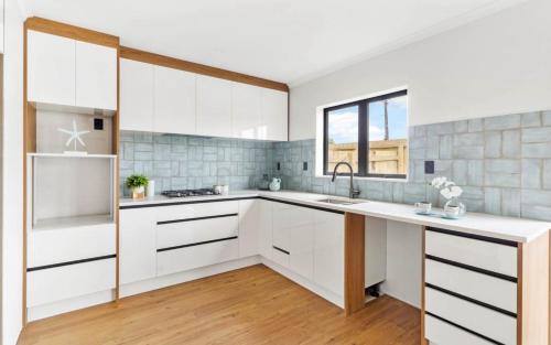 a kitchen with white cabinets and a sink at Holiday Home at Huia Road in Auckland