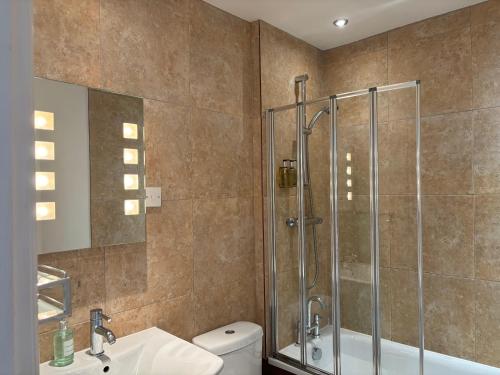 a bathroom with a shower and a toilet and a sink at Dale Head Hall Lakeside Hotel in Keswick