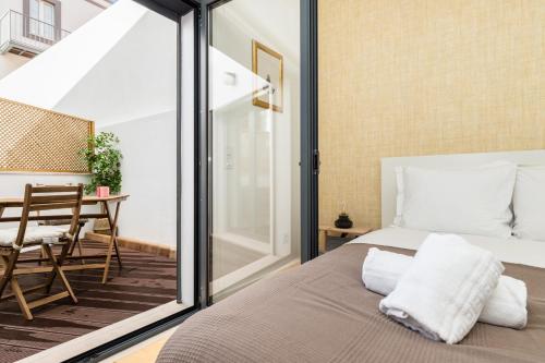 a bedroom with a bed and a balcony with a table at Belem Design Apartments by Homing in Lisbon