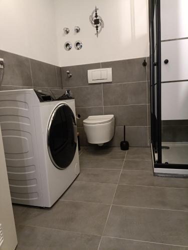 Un baño con lavadora y un inodoro. en Ferienwohnung ENZIAN - nähe Kapellplatz - öffentlicher Parkplatz - Aufzug, en Altötting