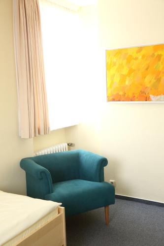 a room with a blue chair and a bed at Bürgermeisterkapelle in Hildesheim