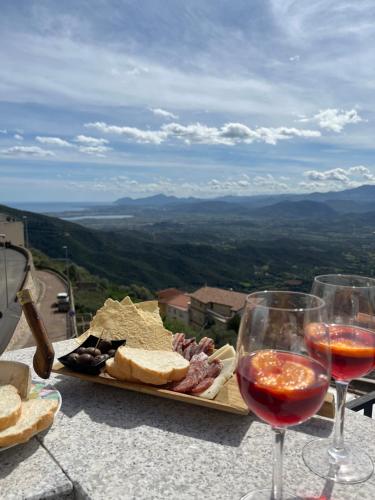 due bicchieri di vino e un vassoio di formaggi e salumi di Window on the Ogliastra apartment in Baunei a Baunei