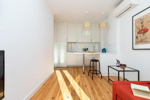 a kitchen and living room with white cabinets and a wooden floor at Belem Design Apartments by Homing in Lisbon
