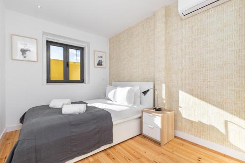 a white bedroom with a bed and a window at Belem Design Apartments by Homing in Lisbon