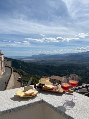 zwei Gläser Wein und Käse auf einer Kante mit Aussicht in der Unterkunft Su Murcone Appartamento Baunei in Baunei