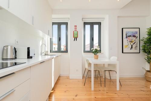 a kitchen with white counters and a white table at Belem Design Apartments by Homing in Lisbon