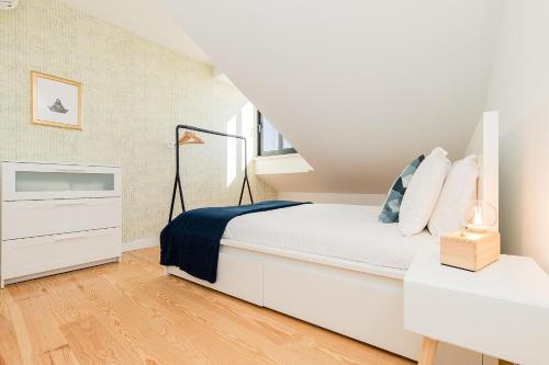 a white bedroom with a bed and a dresser at Belem Design Apartments by Homing in Lisbon