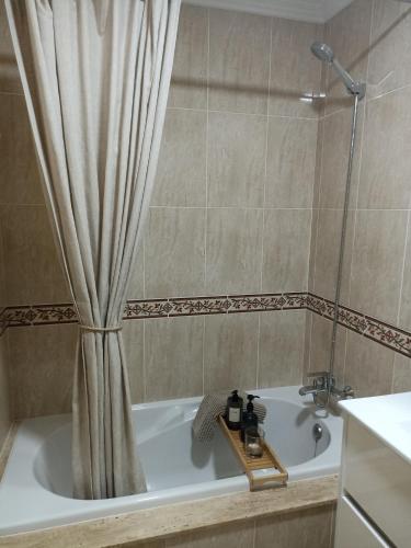 a bathroom with a tub with a shower curtain at EL ATICO in Caldas de Reis
