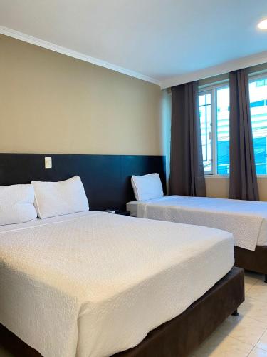 a hotel room with two beds and two windows at Holiday Sai Hotel in San Andrés
