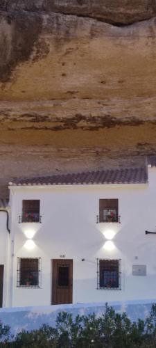 a white building with windows and lights on it at Casa Cueva Las Chicas del Puente in Setenil