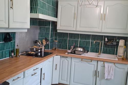 une cuisine avec des armoires blanches et un évier dans l'établissement Large house with garden close Olympics and Paris, à Argenteuil