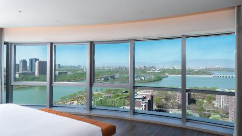a bedroom with a view of the water in a city at EVEN Hotel Yinchuan Yuehai by IHG in Yinchuan